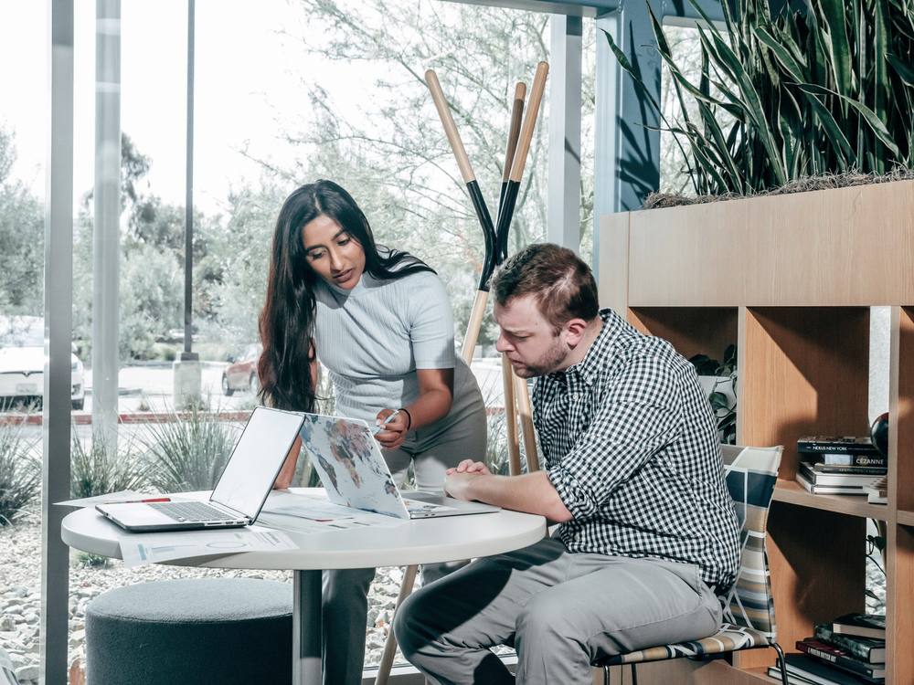 Two colleagues reviewing work on a laptop