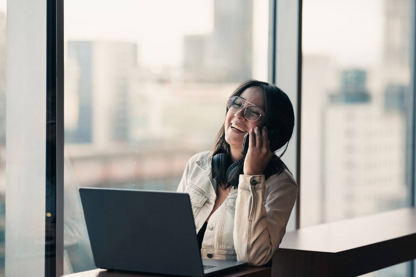 A professional smiling during a phone call at her laptop