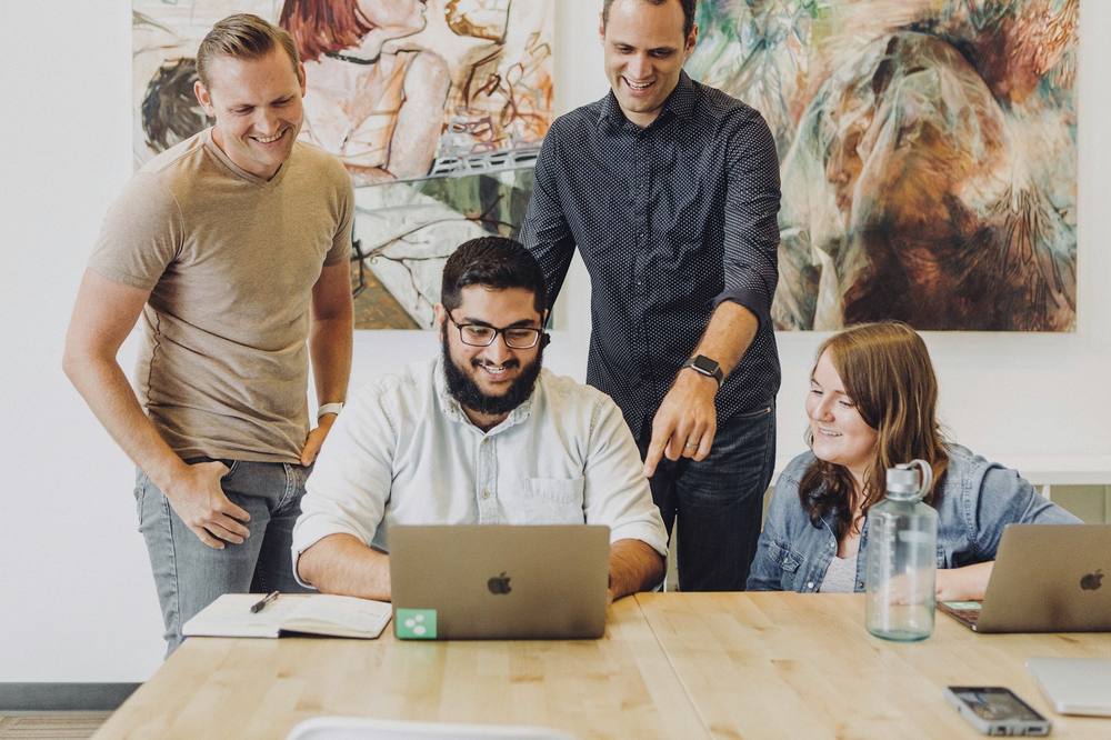 Colleagues gathered around a laptop